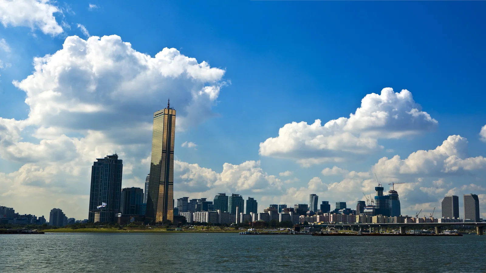 Seoul skyline along the Han River, with the 63 Building rising above the water on a clear day.