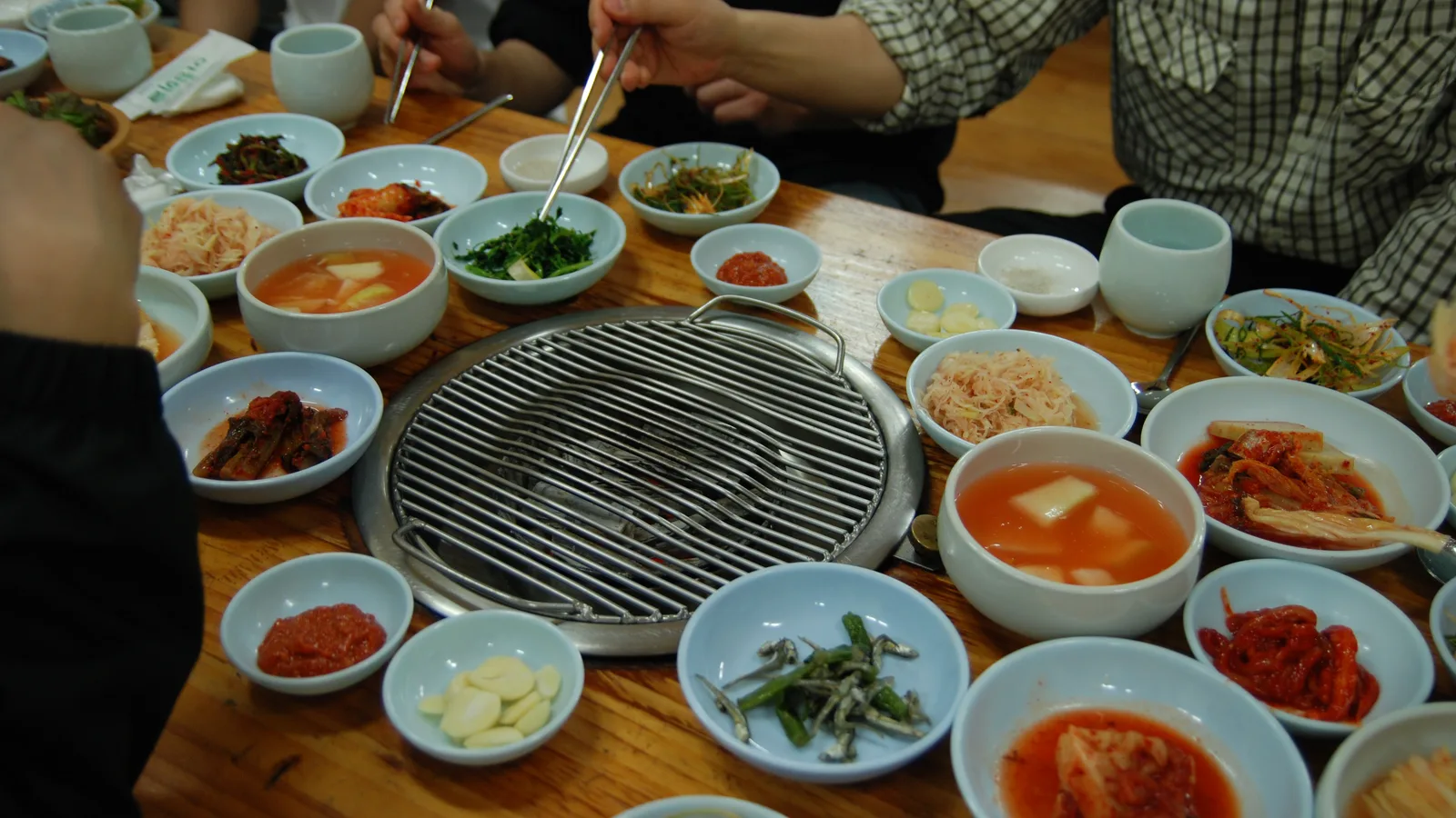 A Korean barbecue grill table set with an assortment of banchan side dishes.
