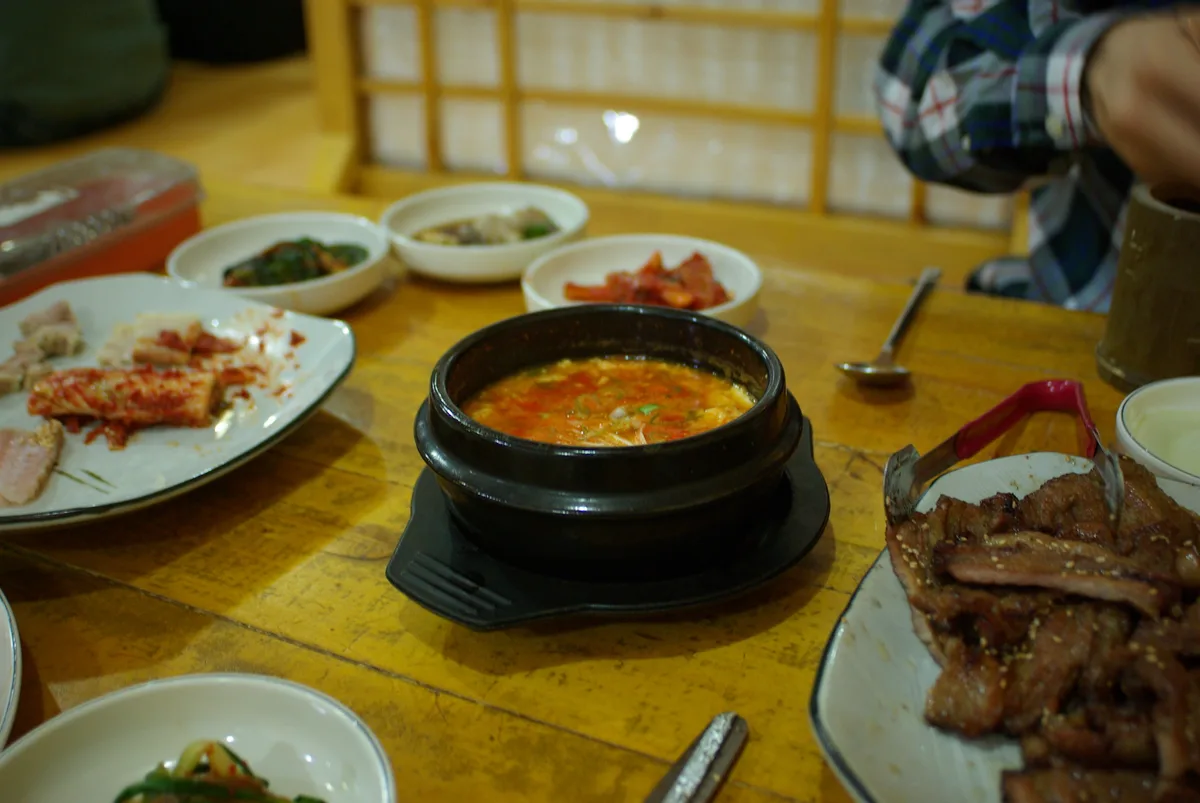 A bubbling pot of sundubu-jjigae (soft tofu stew) served in a traditional stone bowl.