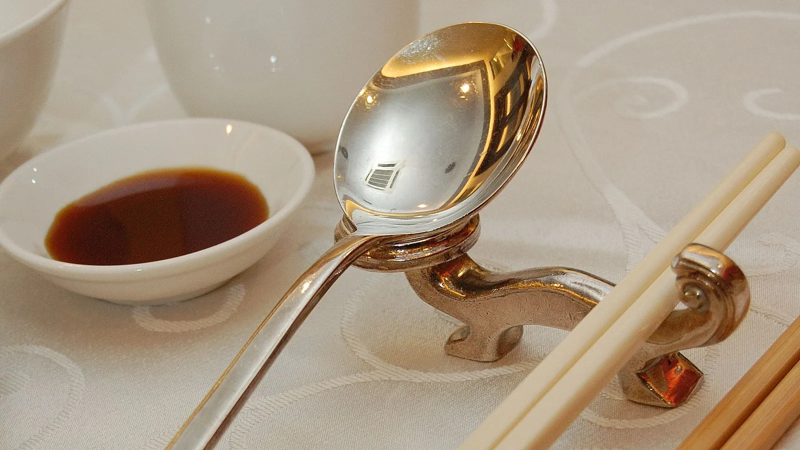 A Korean spoon and a pair of metal chopsticks resting side by side.