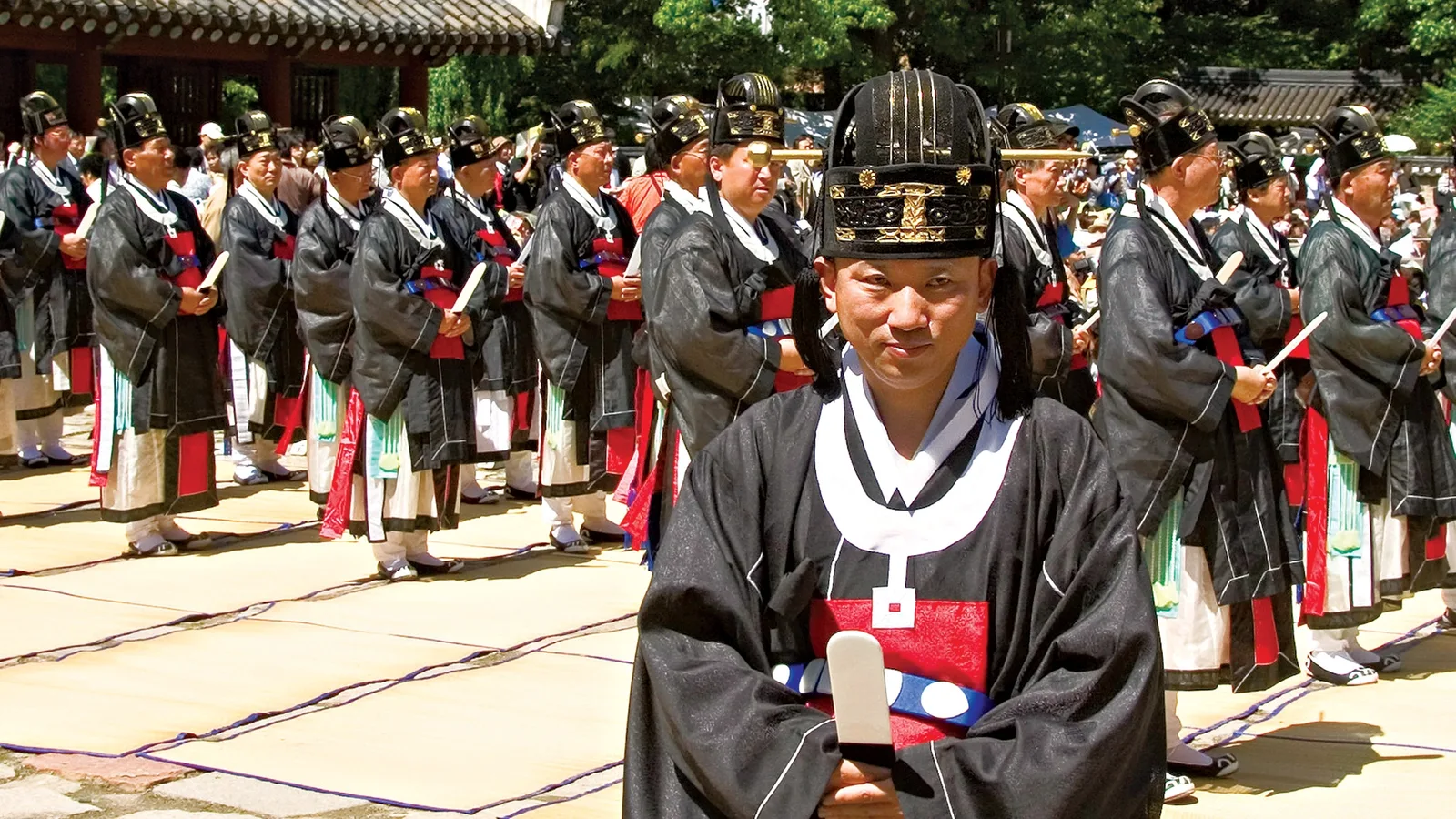 Rows of officials in formal black robes and ceremonial hats standing in strict formation during the Jongmyo Jerye, Korea's Confucian royal ancestral rite.