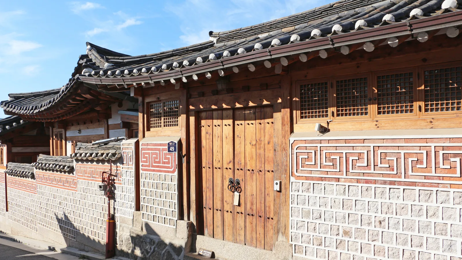 A traditional hanok house and patterned stone wall in Bukchon Hanok Village, Seoul.