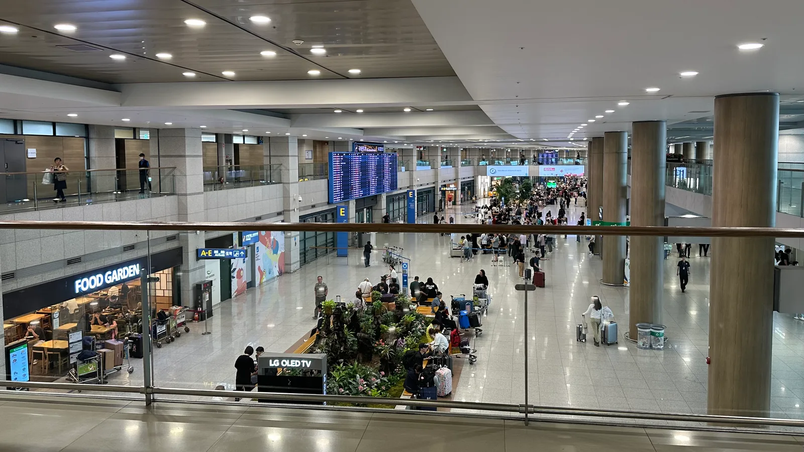 The arrivals hall at Incheon International Airport, with an information board and travelers moving through the terminal.