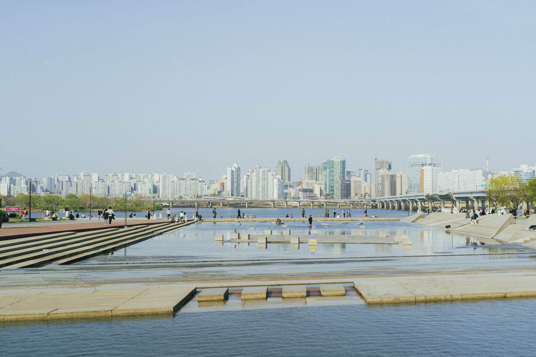 Vibrant spring day overlooking Seoul skyline from Hangang Park, capturing urban life by the Han River.