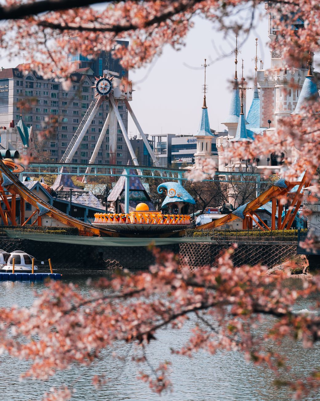 Beautiful cherry blossoms framing Lotte World Magic Island, Seoul in spring.