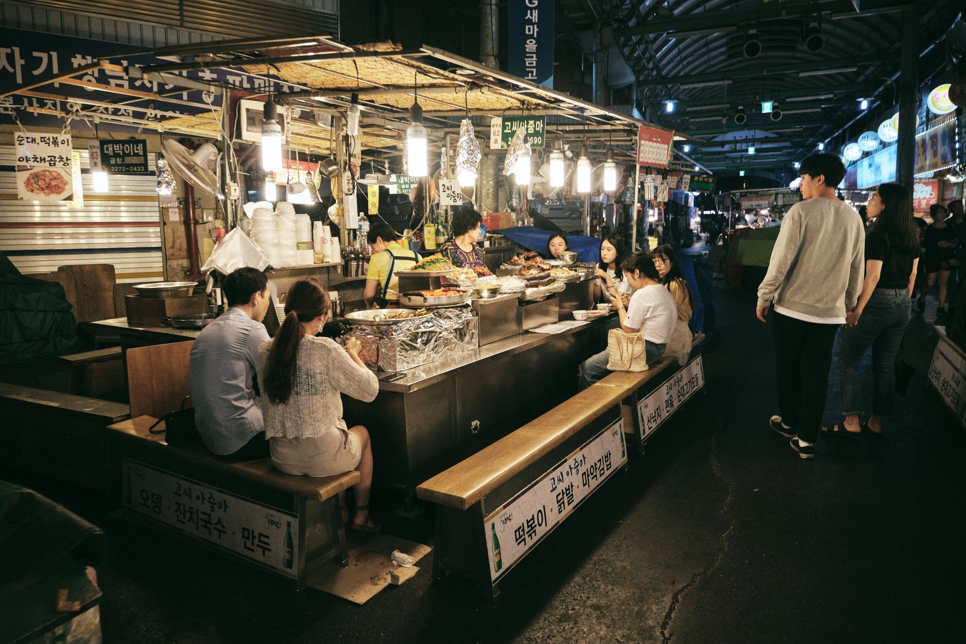 Night market in Seoul bustling with people enjoying street food.