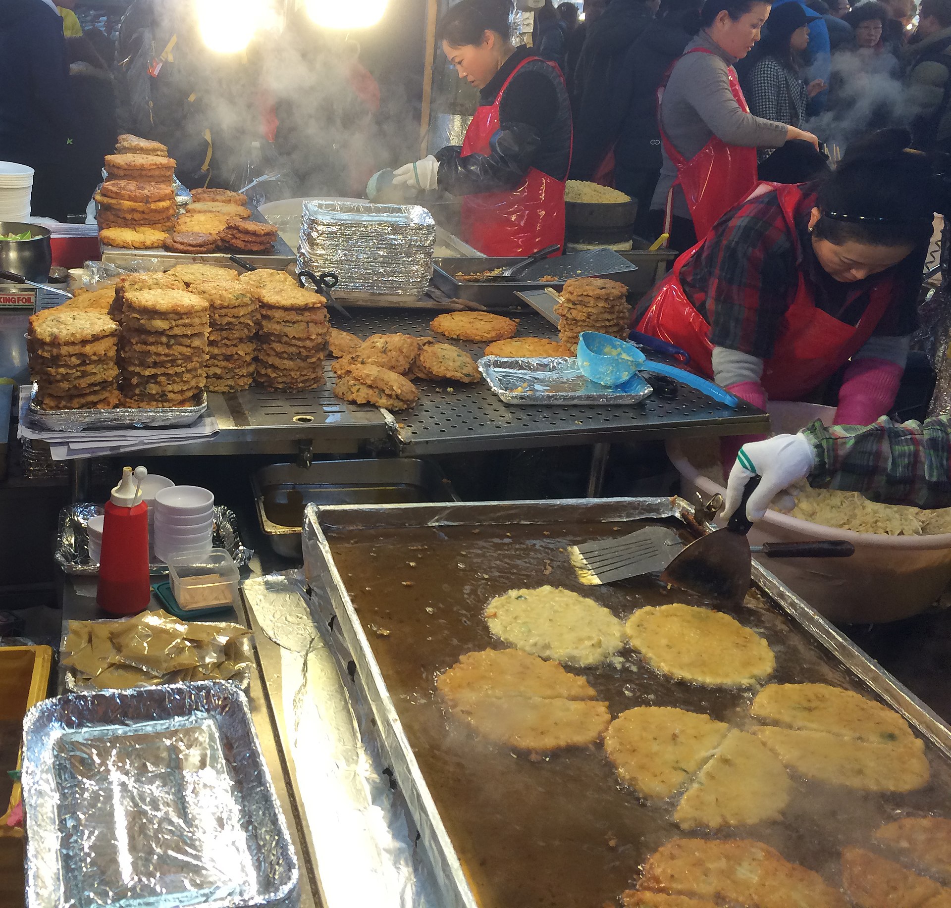 Market vendors frying bindaetteok at Gwangjang Market, Seoul, South Korea