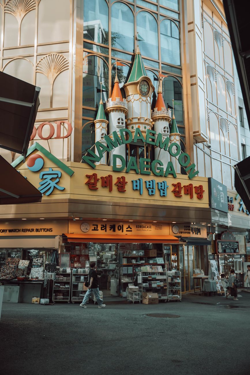 Explore the bustling atmosphere of Namdaemun Market, Seoul with colorful storefronts and lively street activity.