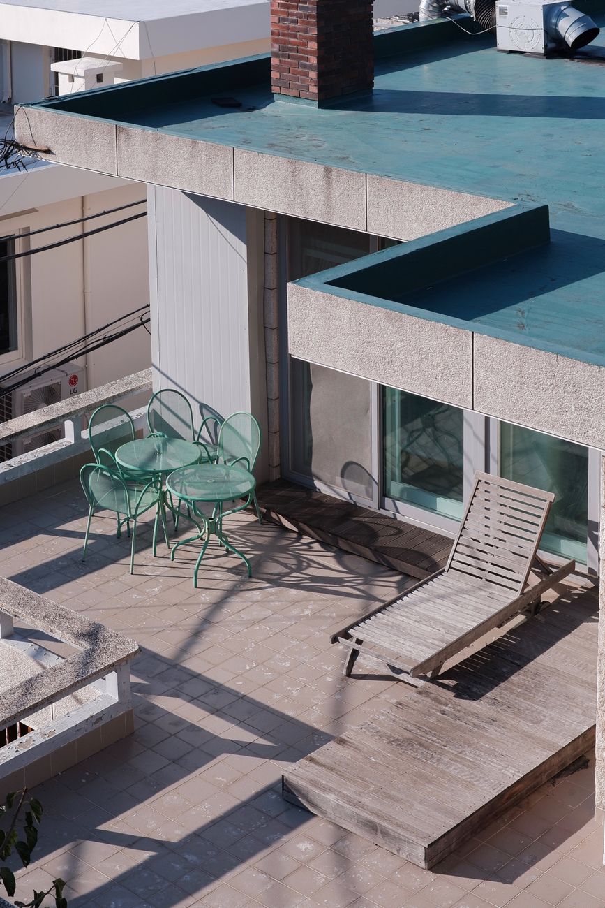 High angle view of a modern rooftop terrace in Seoul with sun loungers and outdoor furniture.