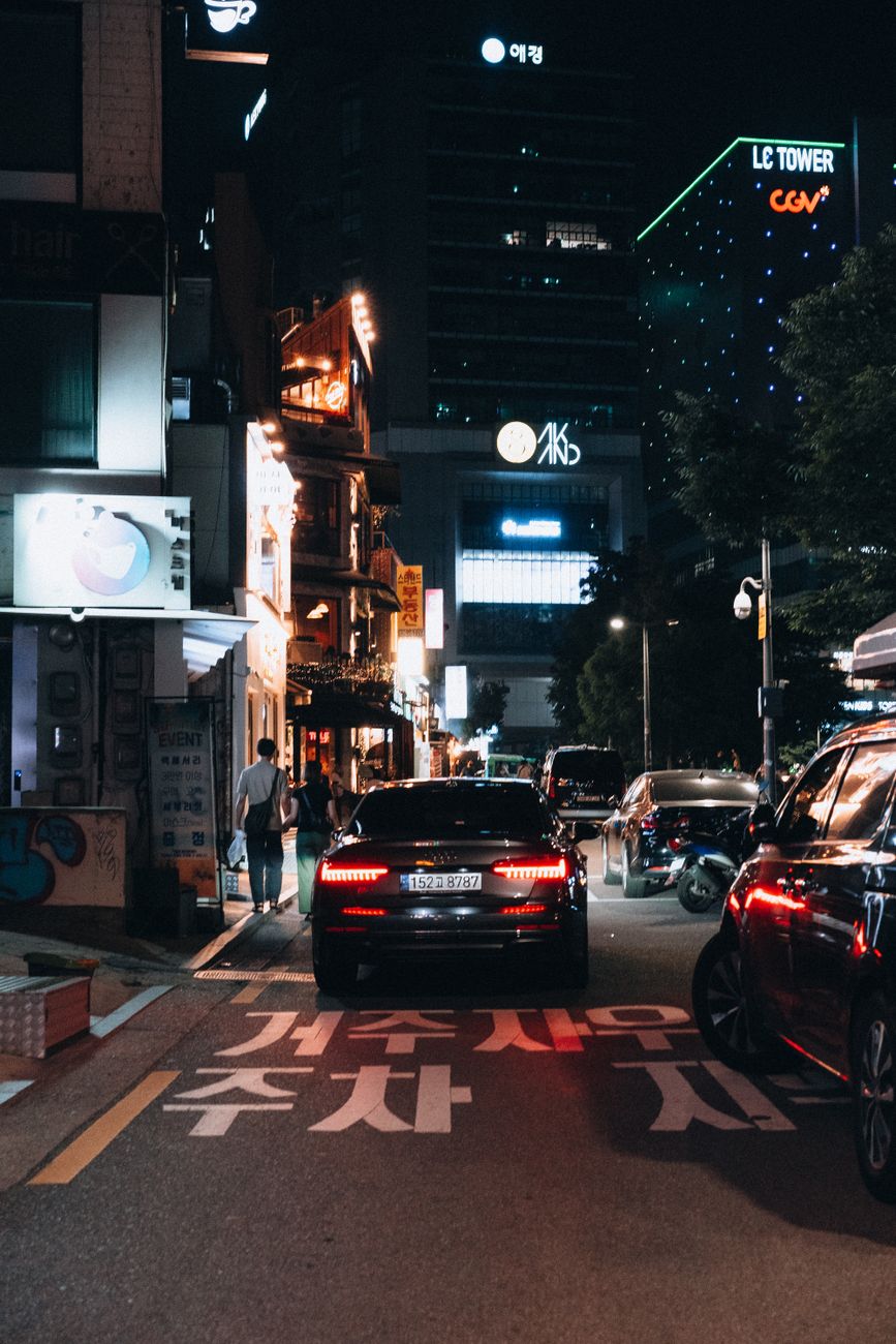 Vibrant night view of a bustling city street with cars and illuminated buildings.