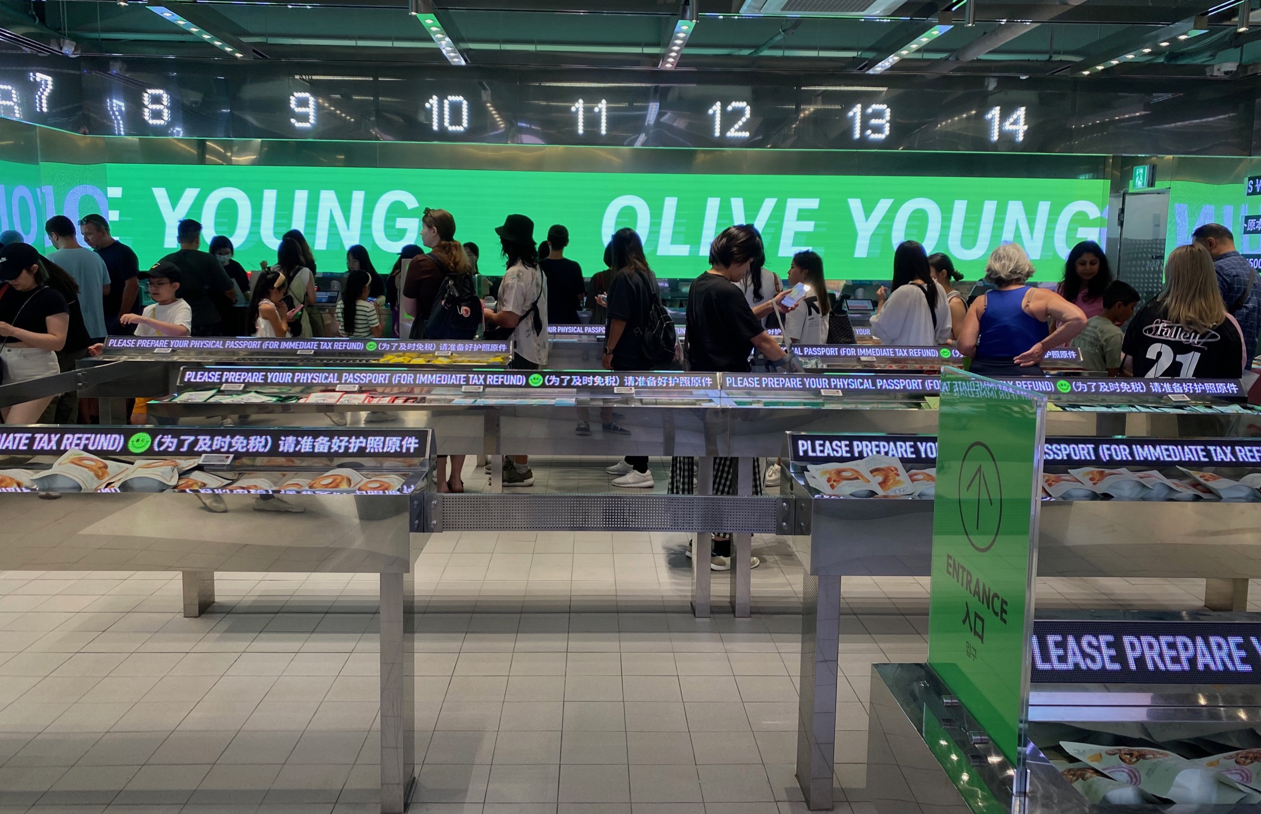 Shoppers browsing inside an Olive Young store in Myeongdong, Seoul, beneath a large green and white OLIVE YOUNG sign.