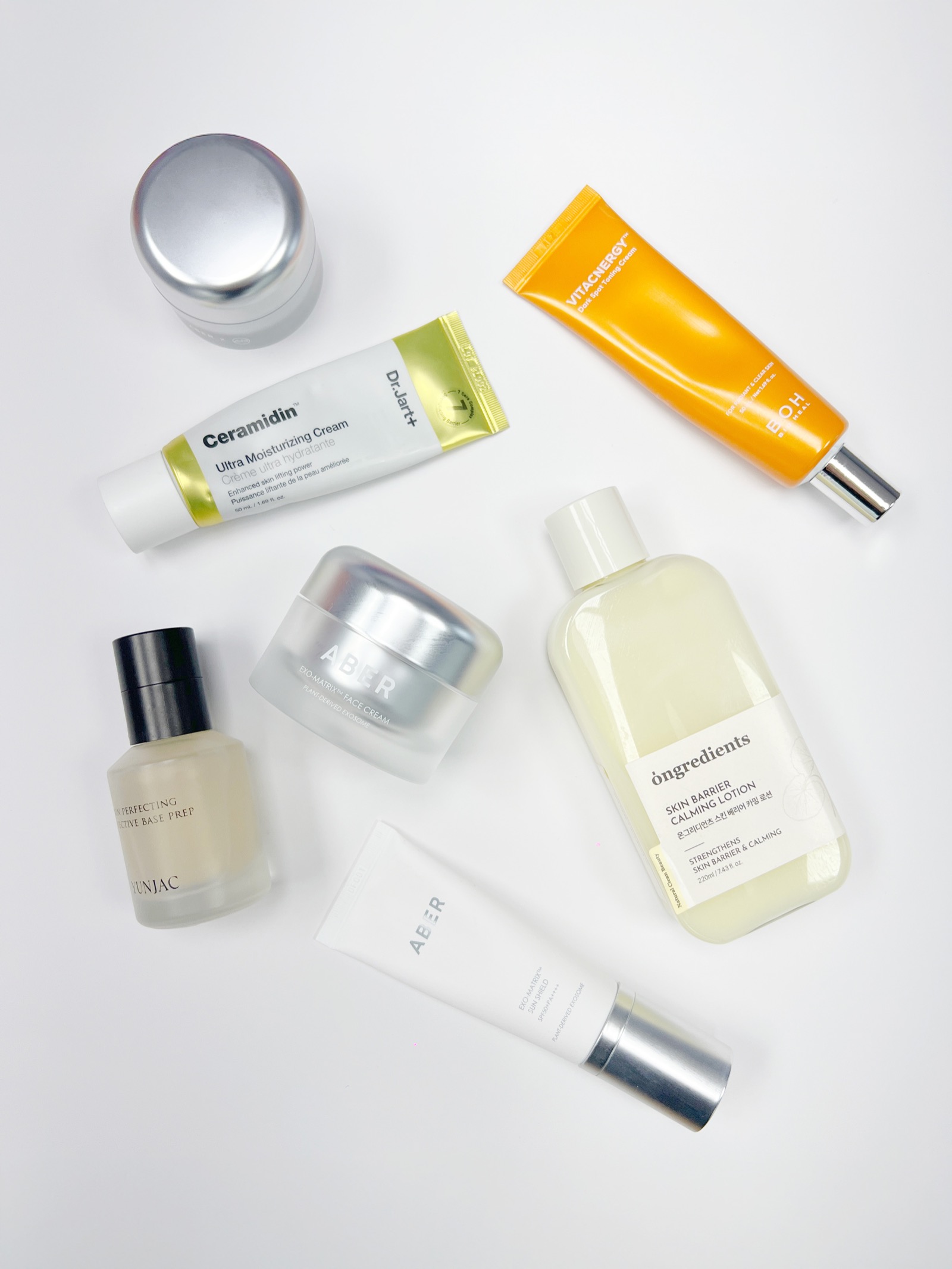 A flat-lay of Korean skincare products, including moisturizers, a toning lotion, and a sunscreen tube, arranged on a white background.