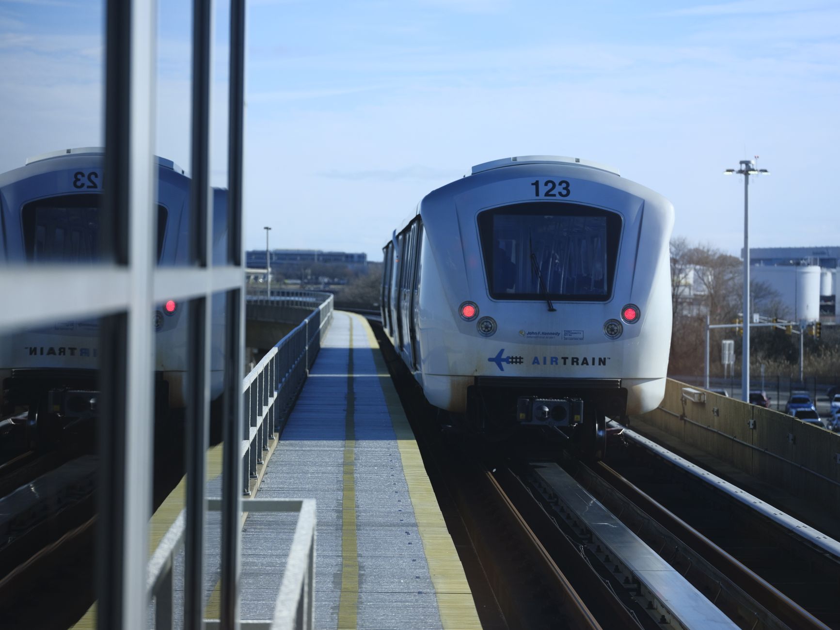 AirTrain approaches JFK airport station in New York on a clear day.