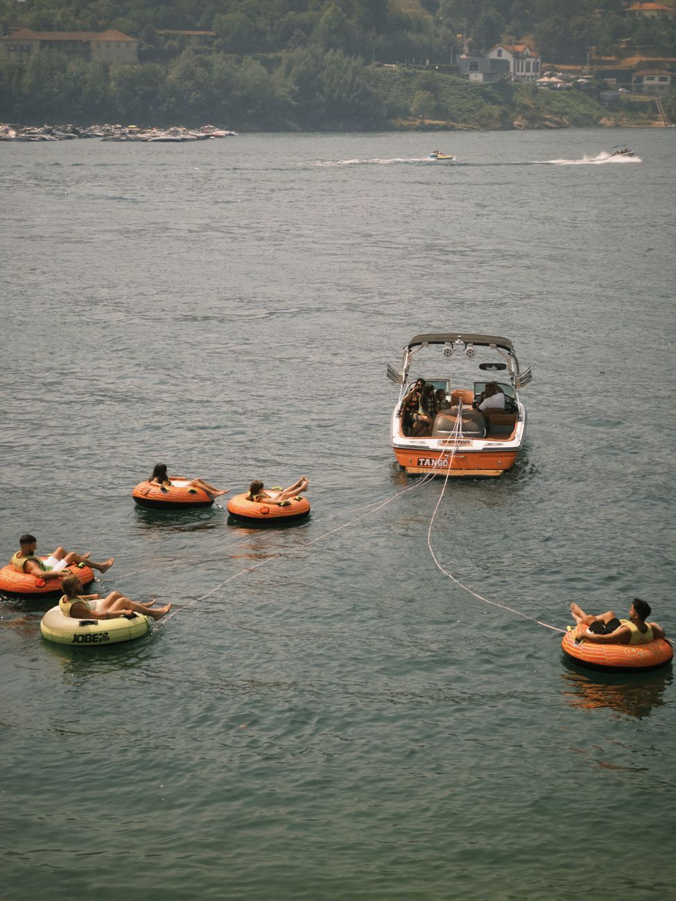 Group enjoying summer day on lake with boat and inner tubes, perfect for leisure and adventure.