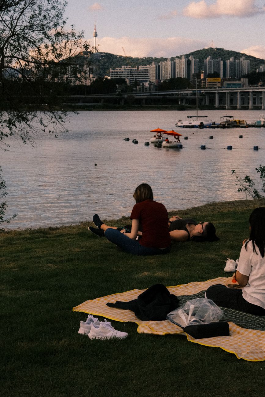 A peaceful picnic scene by the Han River, capturing the city skyline and tranquil waters.