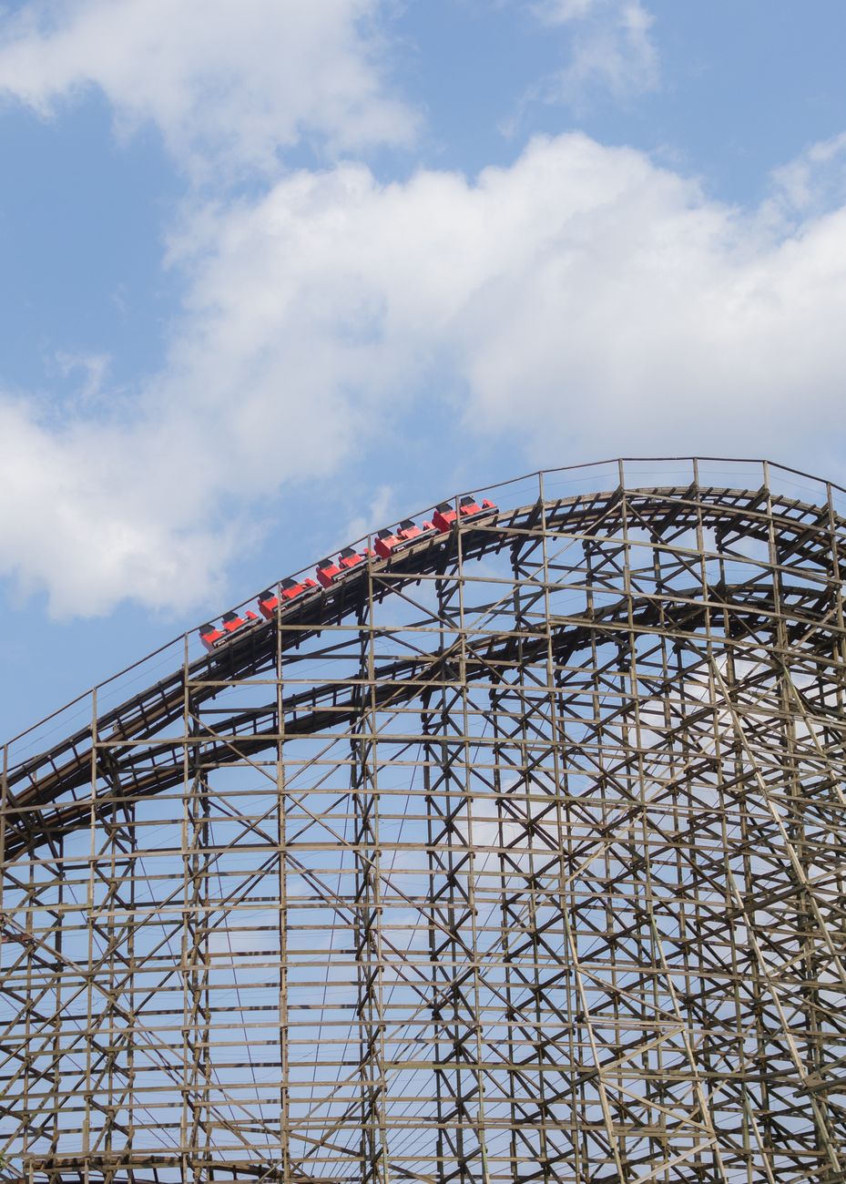 A thrilling ride on a wooden roller coaster set against a bright blue sky, capturing the excitement of an amusement park.
