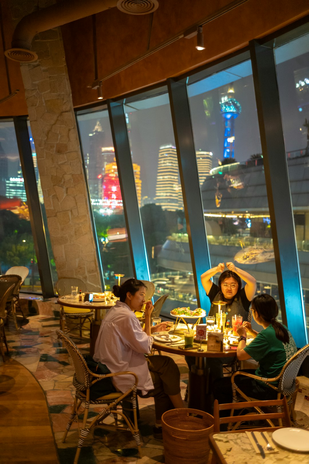 Three people dining in a restaurant with a city view.