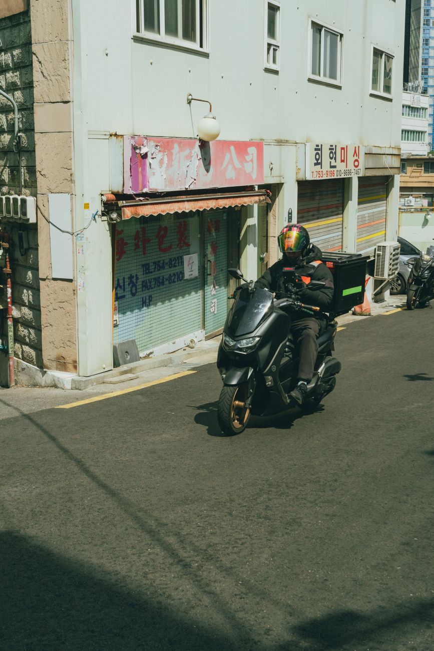 A scooter delivery rider on a calm street in Seoul, South Korea.