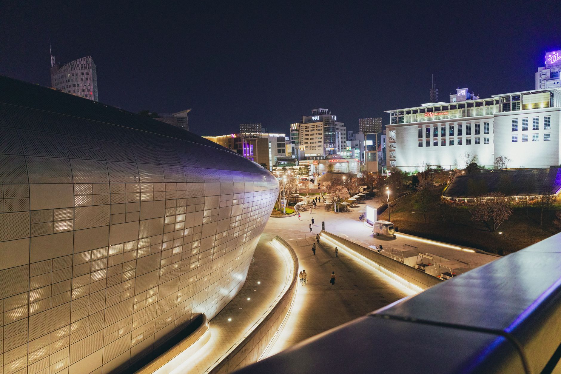 A stunning night shot of Dongdaemun Design Plaza in Seoul with illuminated cityscape.