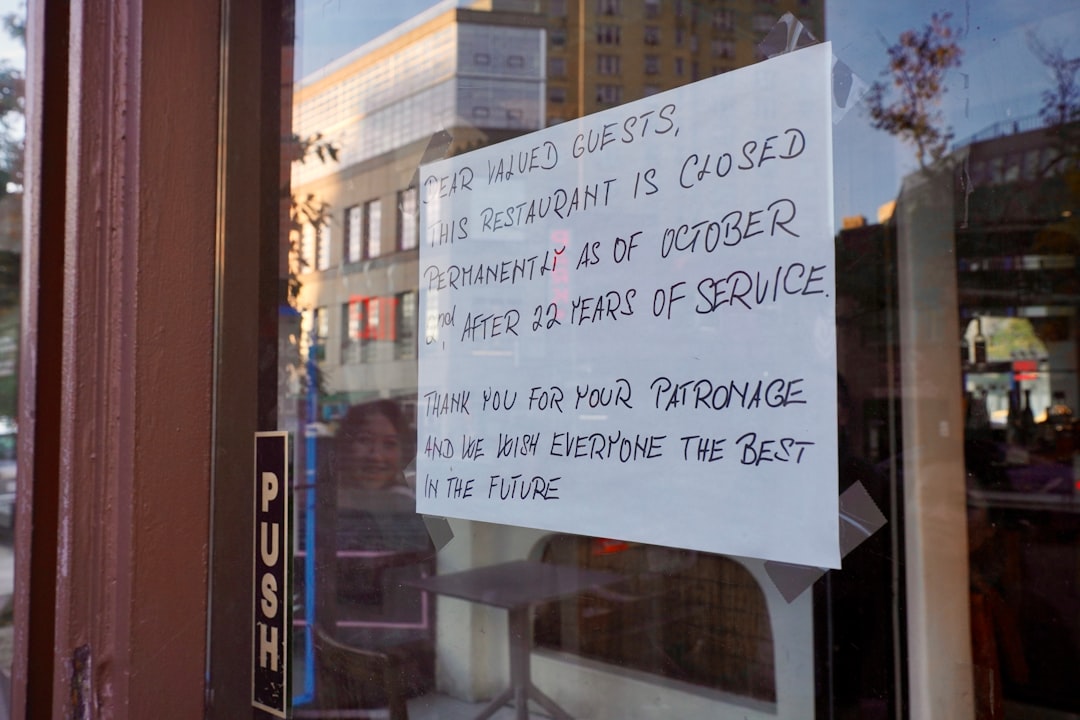 A handwritten sign on the window of a closed restaurant in New York City announces its permanent closure after 22 years of service.