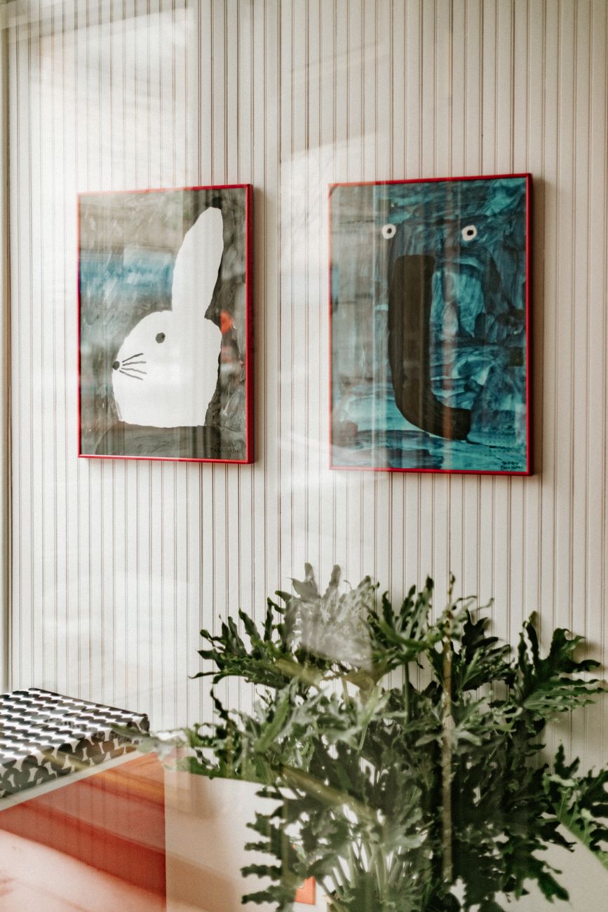Minimalist interior with modern art paintings and houseplant reflection.