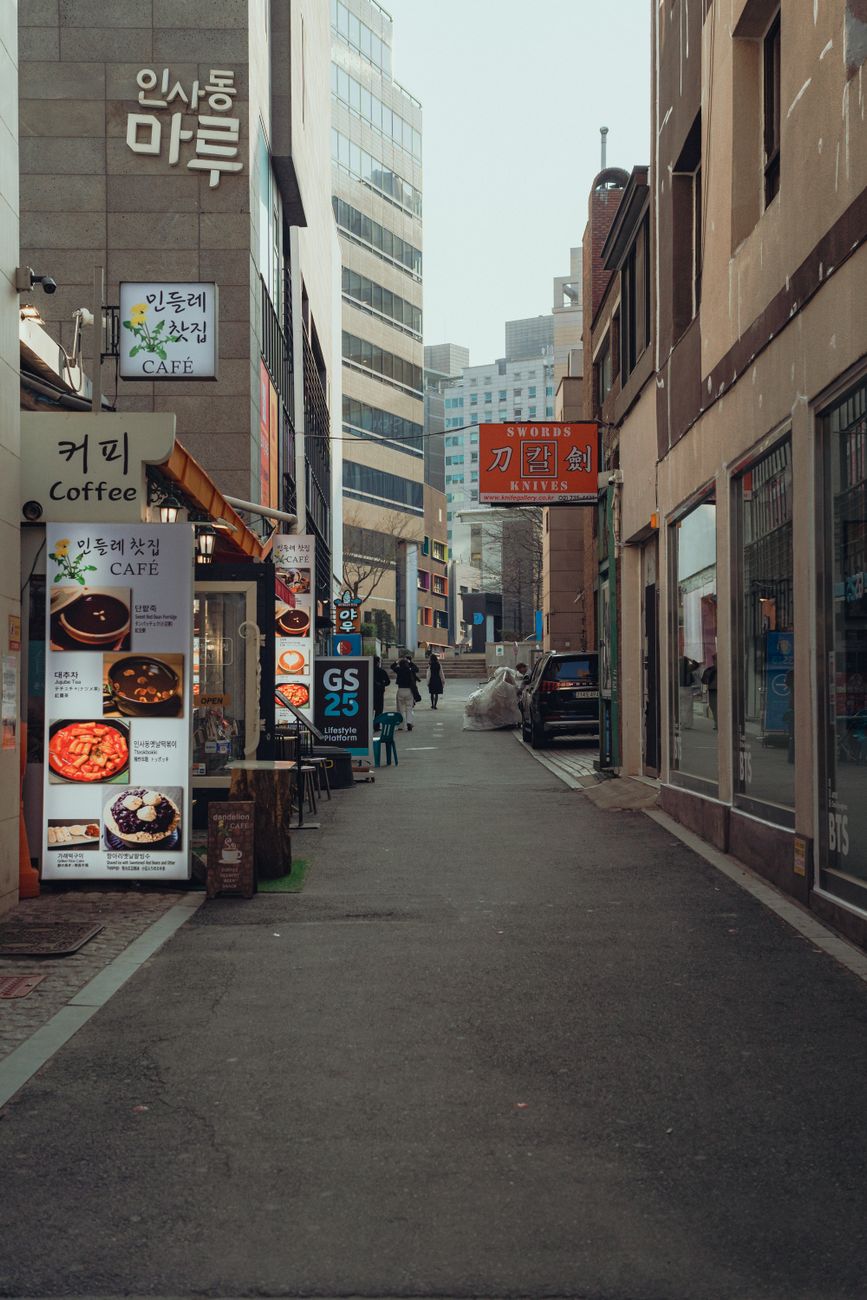 Exploring a bustling street in Seoul lined with local cafes and shops in a vibrant urban setting.