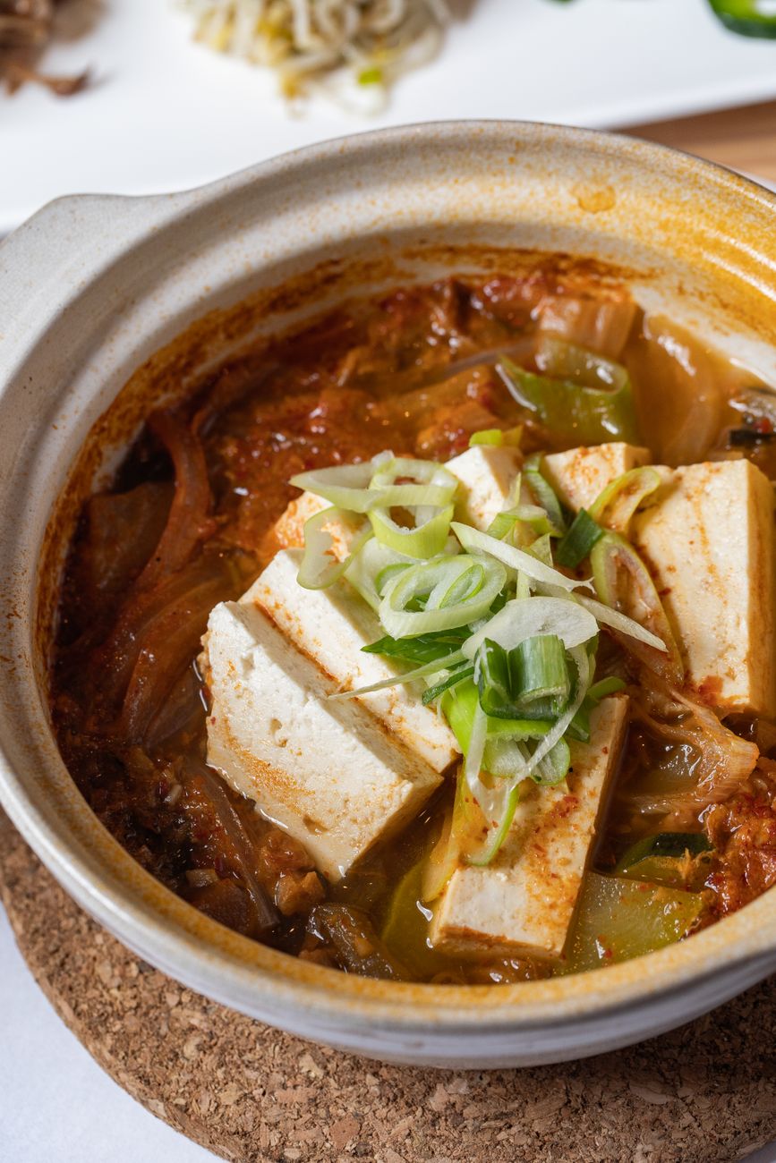 Close-up of delicious Korean kimchi stew with tofu and vegetables in a clay pot.