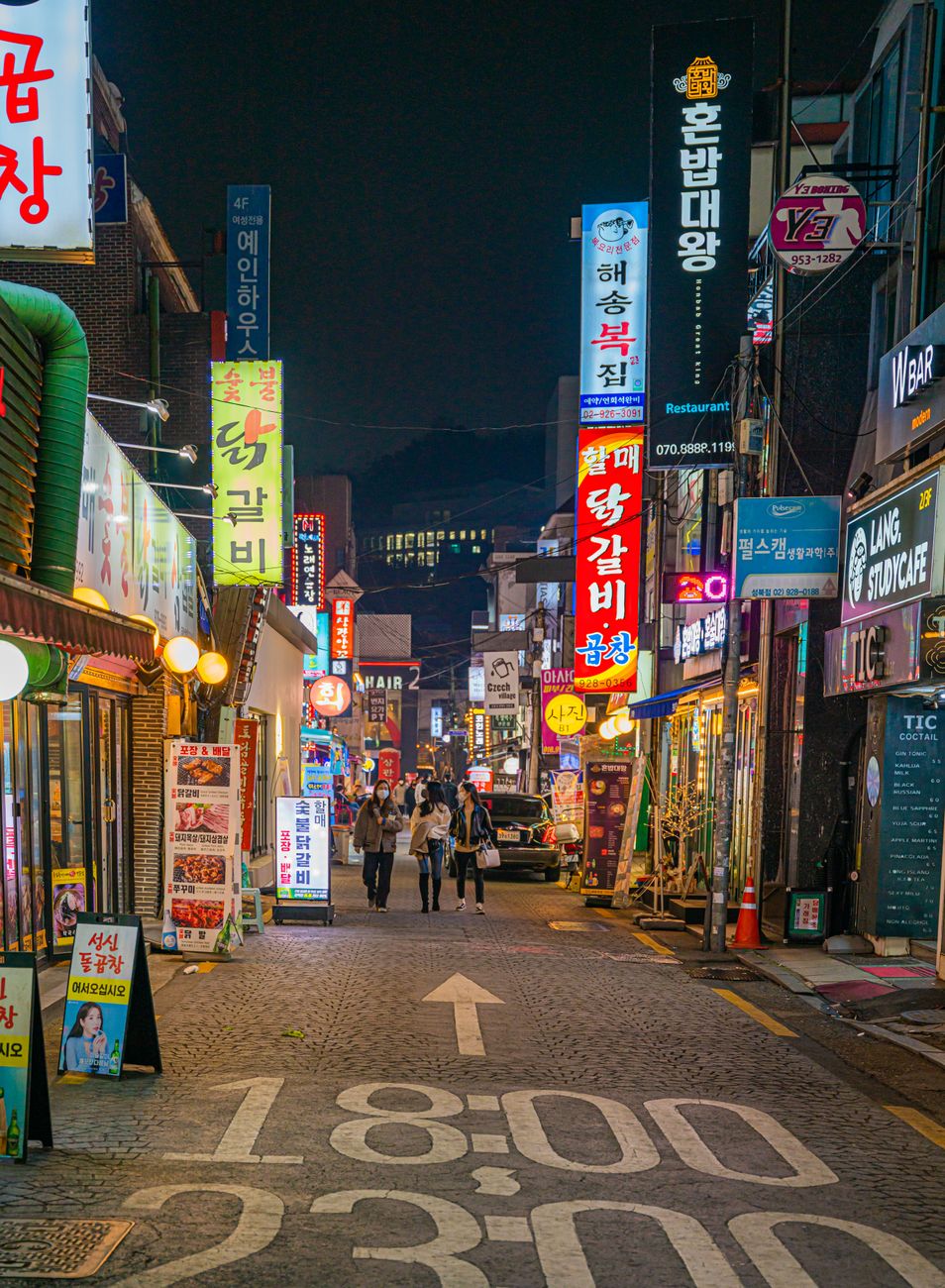 Vibrant night street in Seoul with colorful neon signs and pedestrians, capturing urban life.