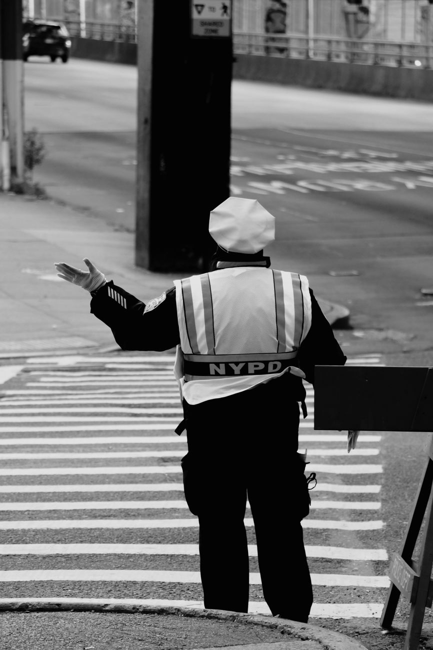 Black and white image of an NYPD officer managing street traffic in New York City.