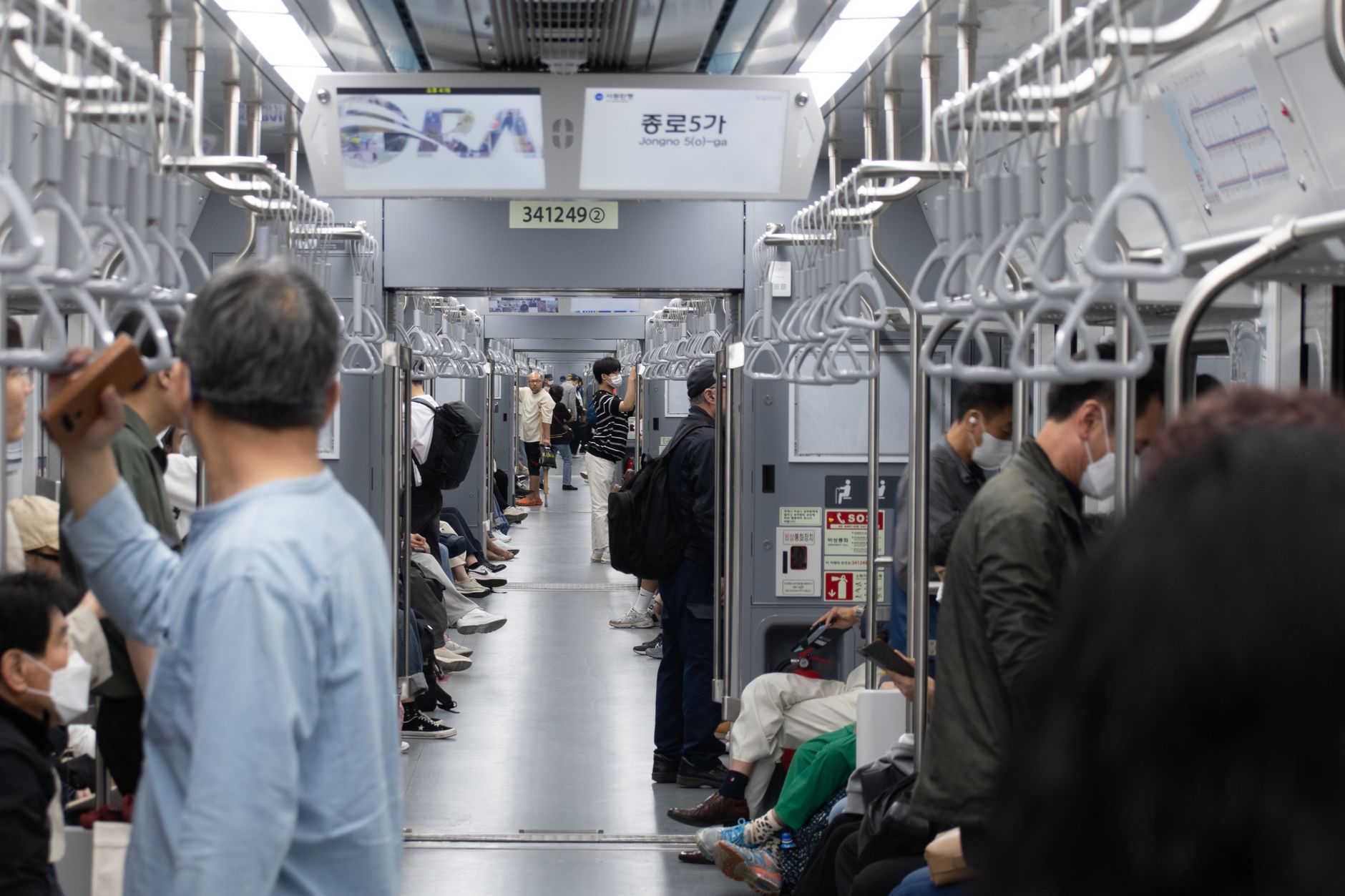 A busy subway scene in Seoul with diverse commuters.