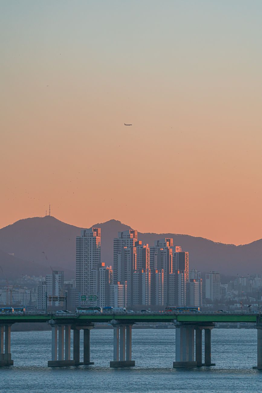 A stunning view of Seoul's skyline at sunset featuring a bridge over a body of water.