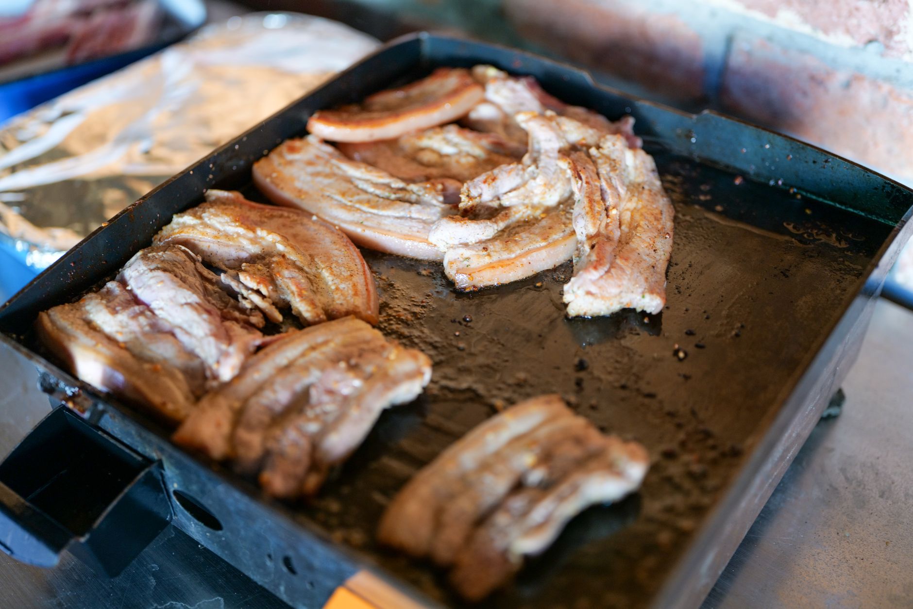 Close-up of succulent roasted pork belly slices sizzling on a grill pan, capturing the essence of Italian cuisine.