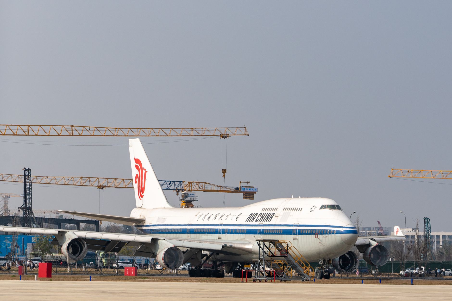 Air China Boeing 747 parked at an airport with construction cranes in the background.