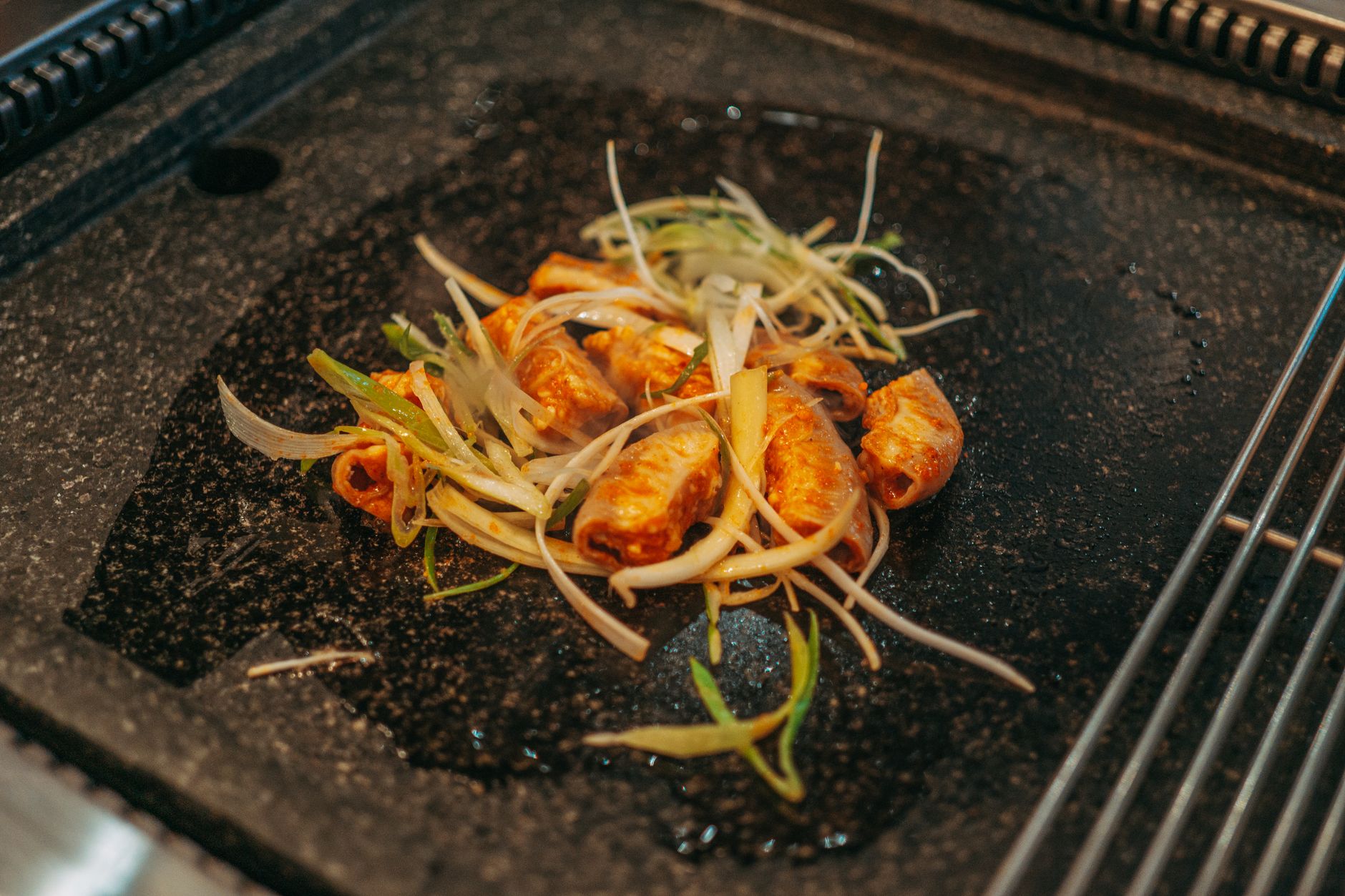 Close-up of kimchi and sliced vegetables cooking on a hot grill, a mouthwatering Korean dish.