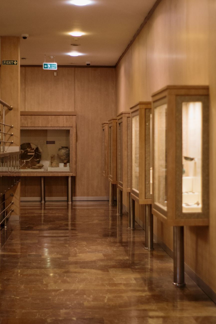 Dimly lit museum corridor highlighting wooden display cases and historical artifacts.