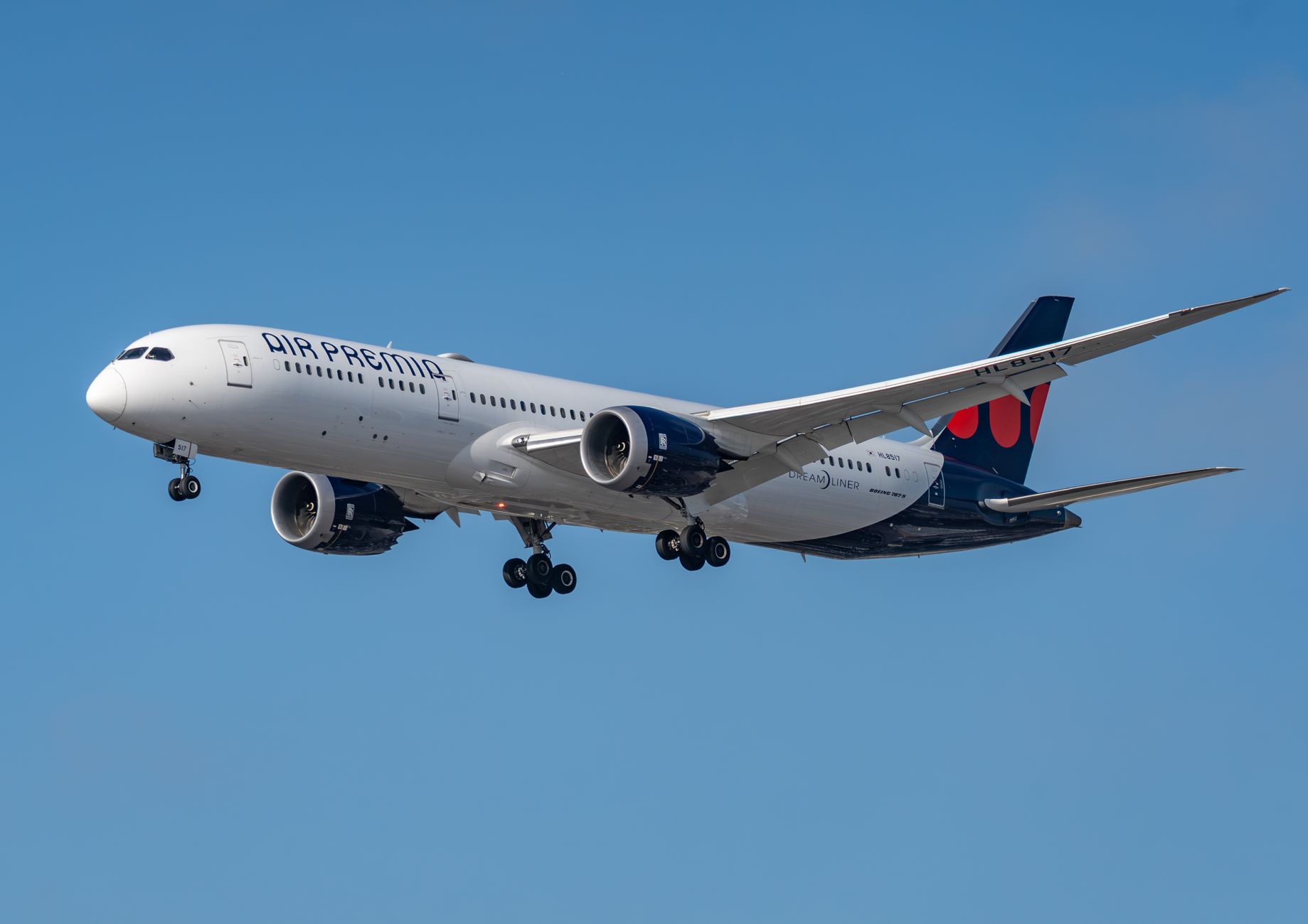Air Premia Boeing 787 Dreamliner landing at Los Angeles airport against a clear blue sky.