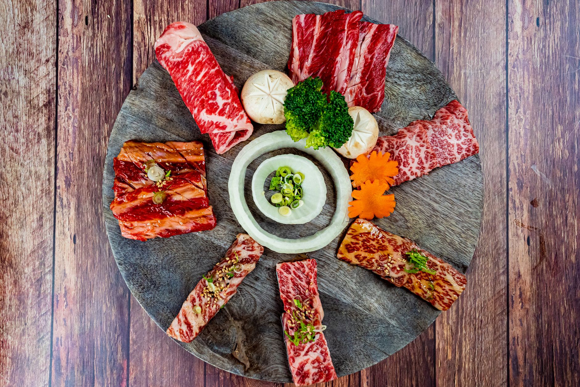 Aesthetic top view of a colorful meat and vegetable platter arranged on a wooden tray.