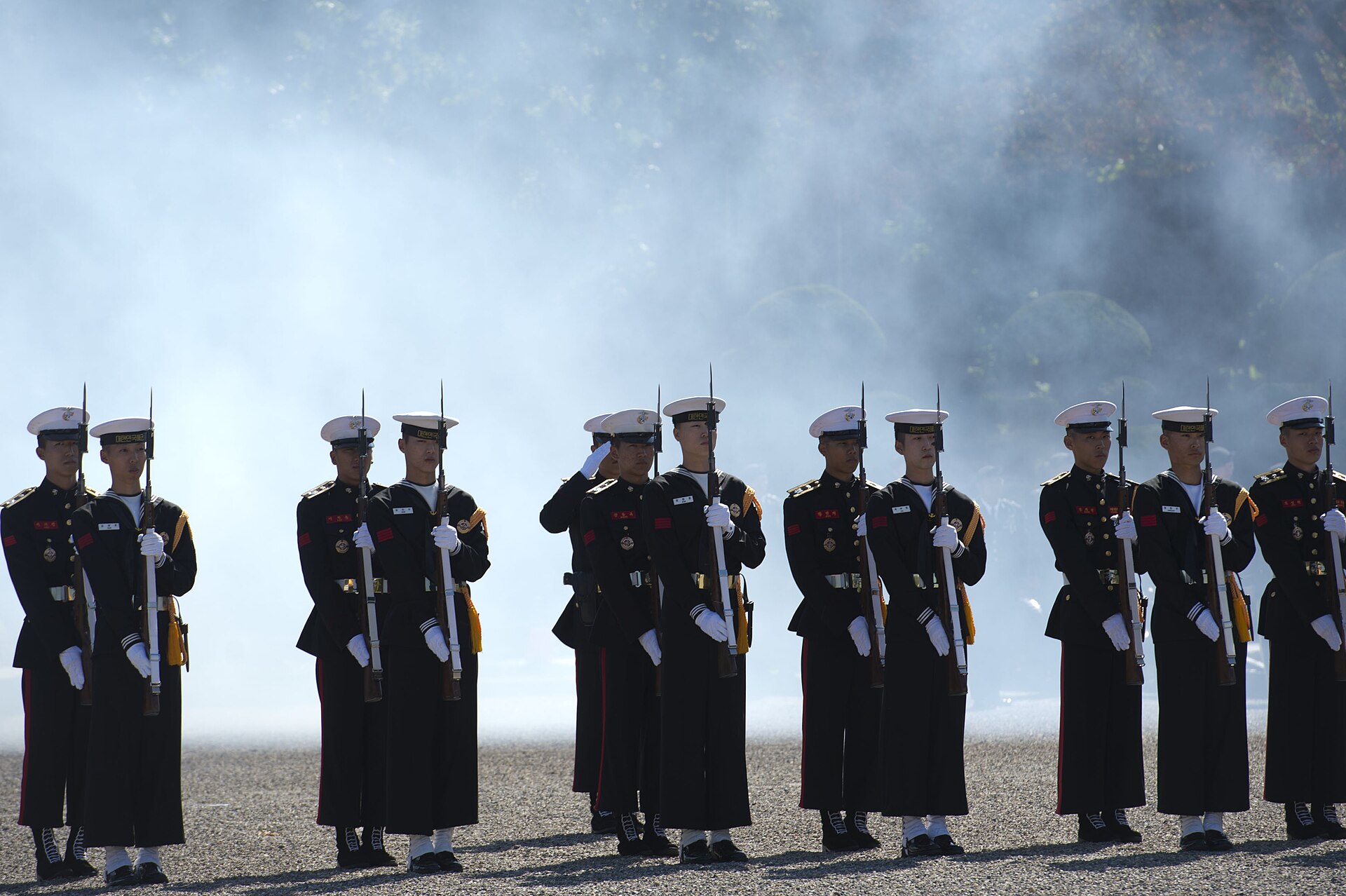South Korean service members stand at attention as smoke from a cannon salute rises behind them during a change of command ceremony for the United Nations…