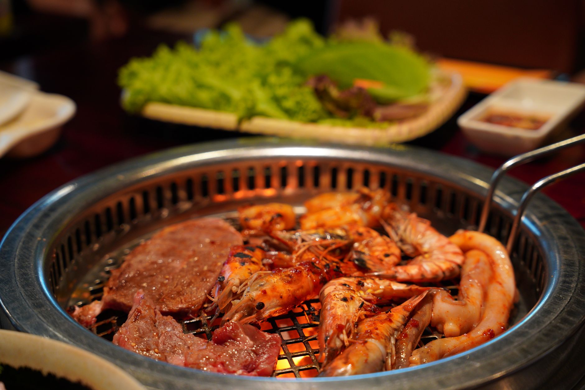 Close-up of grilled shrimp, sausages, and meat on a barbecue grill, perfect for a gourmet meal.
