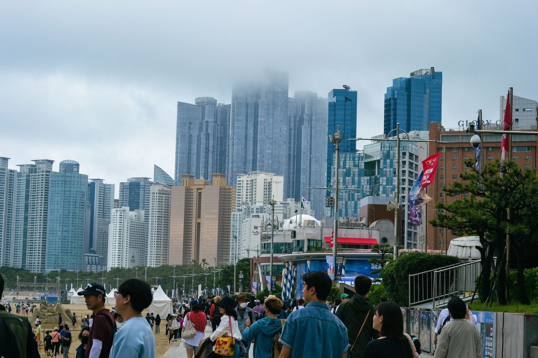 Vibrant scene of Haeundae Beach in Busan with towering skyline surrounded by tourists enjoying the summer.