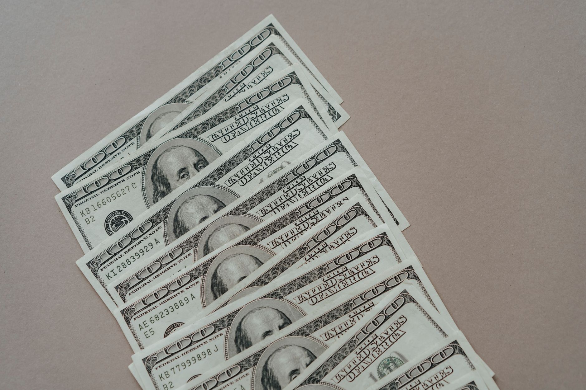 A close-up of multiple US dollar bills arranged on a neutral surface.